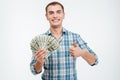 Cheerful successful young man holding money and showing thumbs up Royalty Free Stock Photo