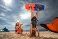 Surfing couple posing on the beach. Surfer woman standing on her head with kiteboard Royalty Free Stock Photo