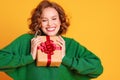 Cheerful surprised woman laughs with closed eyes holds a Christmas gifts on a colored yellow background