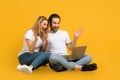 Cheerful surprised young european family sit on floor, look at laptop, gesticulate