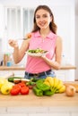 Cheerful svelte young woman eating vegetable salad in home kitchen Royalty Free Stock Photo