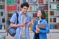 Cheerful talking college students male and female inside library