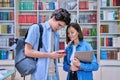 Cheerful talking college students male and female inside library