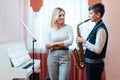 Cheerful teacher with student boy learning saxophone lessons at school Royalty Free Stock Photo