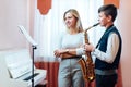 Cheerful teacher with student boy learning saxophone lessons at school Royalty Free Stock Photo