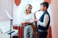 Cheerful teacher with student boy learning saxophone lessons at school Royalty Free Stock Photo