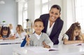 Cheerful teacher working with elementary school boy at his desk Royalty Free Stock Photo