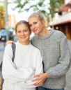 Cheerful teen girl and her mother embracing on city street Royalty Free Stock Photo