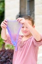 Cheerful teen girl holding a purple slime and looking through. Royalty Free Stock Photo