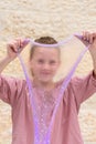 Cheerful teen girl holding a purple slime and looking through. Royalty Free Stock Photo