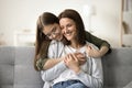 Cheerful teen girl hugging young mother from behind with love