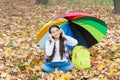 Cheerful teen girl relax in fall forest or park while listening music in headphones near school backpack under colorful Royalty Free Stock Photo