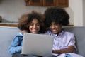Cheerful teenage African couple sit on sofa with laptop Royalty Free Stock Photo