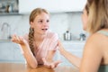 Cheerful teenage girl chatting friendly to mother in home kitchen Royalty Free Stock Photo