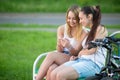 Cheerful teenage girls playing with cellphone on bench Royalty Free Stock Photo