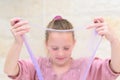 Cheerful teen girl holding a purple slime and looking through. Royalty Free Stock Photo