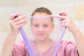 Cheerful teen girl holding a purple slime and looking through. Royalty Free Stock Photo