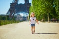 Cheerful toddler girl running near the Eiffel tower