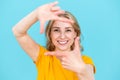 Cheerful toothily smiling woman making frame gesture in studio Royalty Free Stock Photo