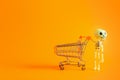 Cheerful toy skeleton with shopping cart on orange background with copy space