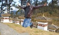 Cheerful traveler man backpacker wearing a biker jacket, jumping hand looking Dochula Dzong architecture of buddhist temple in