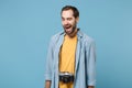 Cheerful traveler tourist man in yellow summer casual clothes with photo camera on neck isolated on blue background