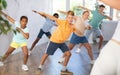 Cheerful tween boy doing dabbing move during dance with group of children