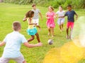 Cheerful tween friends playing with ball outdoors in summer