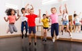 Cheerful tweens jumping with trainer during dance class