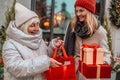 Cheerful two women are having fun in the city street at the Christmas time, laughing and buying presents for their Royalty Free Stock Photo