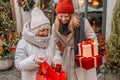 Cheerful two women are having fun in the city street at the Christmas time, laughing and buying presents for their Royalty Free Stock Photo