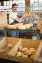 Cheerful waiter in apron holding baguettes