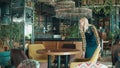 Cheerful waitress is rearranging furniture in the restaurant