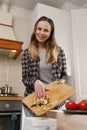 Cheerful white woman composting organic food waste at home. Portrait of friendly female person throwing peels into bokashi