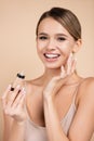 cheerful woman applying face foundation while
