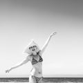 Cheerful woman in beachwear and straw hat on the seashore