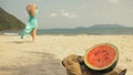 The cheerful woman in blur, against the background of a watermelon on tropical sand beach sea. Portrait attractive girl Royalty Free Stock Photo