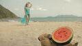 The cheerful woman in blur, against the background of a watermelon on tropical sand beach sea. Portrait attractive girl Royalty Free Stock Photo