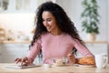 Cheerful Woman Browsing Internet On Digital Tablet While Having Breakfast In Kitchen Royalty Free Stock Photo