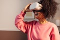 Cheerful woman in casuals standing indoors exploring virtual reality