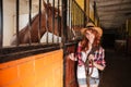 Cheerful woman cowgirl with horse standing in stable Royalty Free Stock Photo