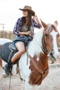 Cheerful woman cowgirl sitting and riding horse in village Royalty Free Stock Photo