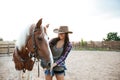 Cheerful woman cowgirl standing and taking care of her horse Royalty Free Stock Photo