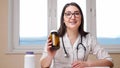 Cheerful woman doctor shows bottles with medicines to camera