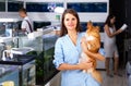 cheerful woman with dog with interest looking at aquarium in pet shop Royalty Free Stock Photo