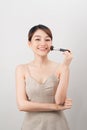 Cheerful woman is doing make up on her face using brush. Beauty routine on white background Royalty Free Stock Photo