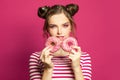 Cheerful woman with donuts on vivid pink background, diet concept