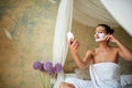 Cheerful  woman facial mask on face sitting in bed and looking at mirror.Beauty and body care concept Royalty Free Stock Photo