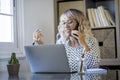 Cheerful woman freelance in smart working busy office home activity alone sitting at the desl in phone call. Concept of online
