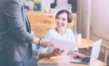 Cheerful woman getting papers from her collegue